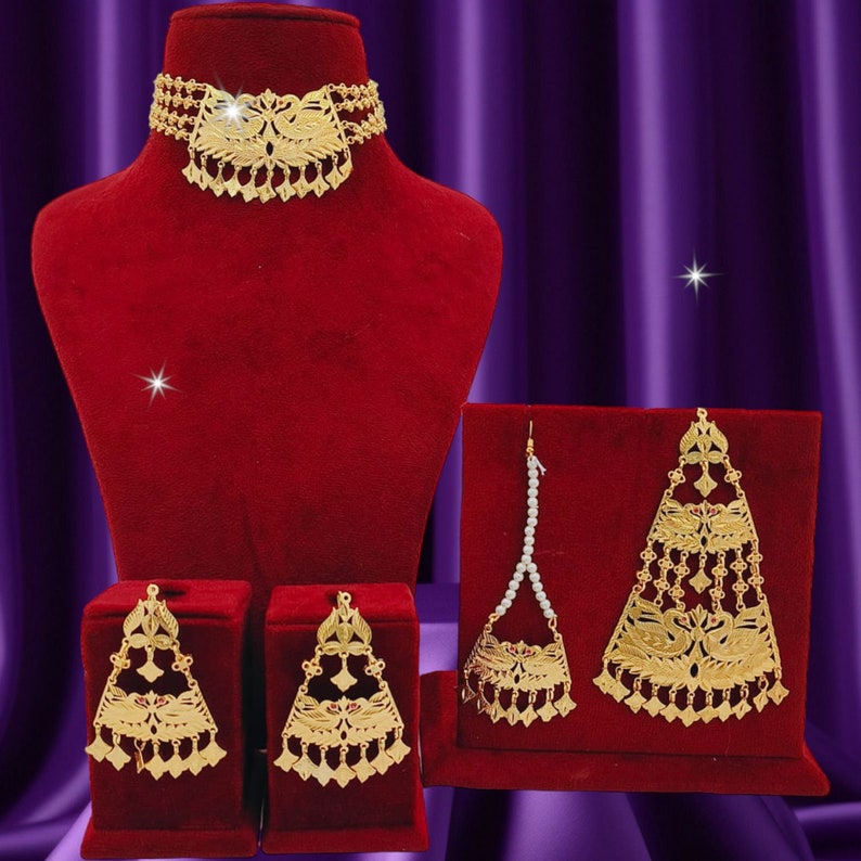 May include: A gold-tone necklace, earrings, and a headpiece with intricate floral and bird designs. The jewelry is displayed on red velvet stands.