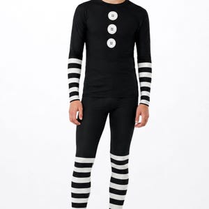May include: A long-sleeve black shirt featuring three white circular button graphics on the chest and black and white horizontal striped sleeves, paired with matching black and white horizontal striped leggings. The text MAX(XX)ART is visible.