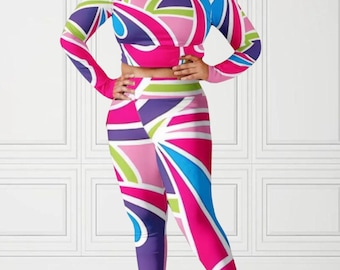 Könnte beinhalten: Ein zweiteiliges Outfit mit einem langärmeligen Crop-Top und Leggings. Der Stoff hat ein farbenfrohes geometrisches Muster in den Farben Pink, Blau, Grün und Lila.
