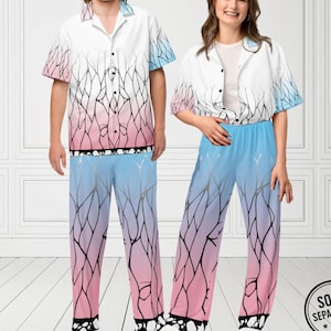 May include: Matching pajama set featuring a white button-down shirt and pants with a gradient design. The shirt and pants transition from pink to blue, with a black tree branch pattern. The set is designed for comfort and style.