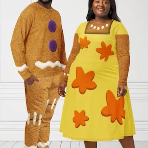 Pode incluir: Uma pessoa vestindo uma roupa com tema de homem de gengibre, incluindo uma blusa de manga comprida e calças combinando. Outra pessoa usa um vestido amarelo com desenhos de flores laranja. As roupas são caprichosas e coloridas.