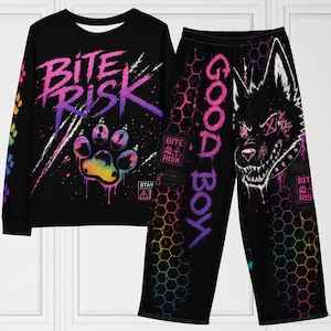 Może przedstawiać: Czarny zestaw bluzy i spodni z efektownym wzorem graficznym. Bluza ma napis "BITE RISK" i odcisk łapy, a spodnie "GOOD BOY" i ilustrację wilka. Oba elementy mają tęczowe akcenty i geometryczne wzory.