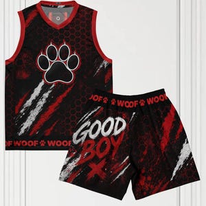 Puede incluir: Un conjunto de camiseta sin mangas y pantalones cortos en negro y rojo con un patrón hexagonal, un gráfico de huella grande en el pecho y el texto "GOOD BOY" y "WOOF" impreso en blanco y rojo sobre la tela con detalles de pinceladas.