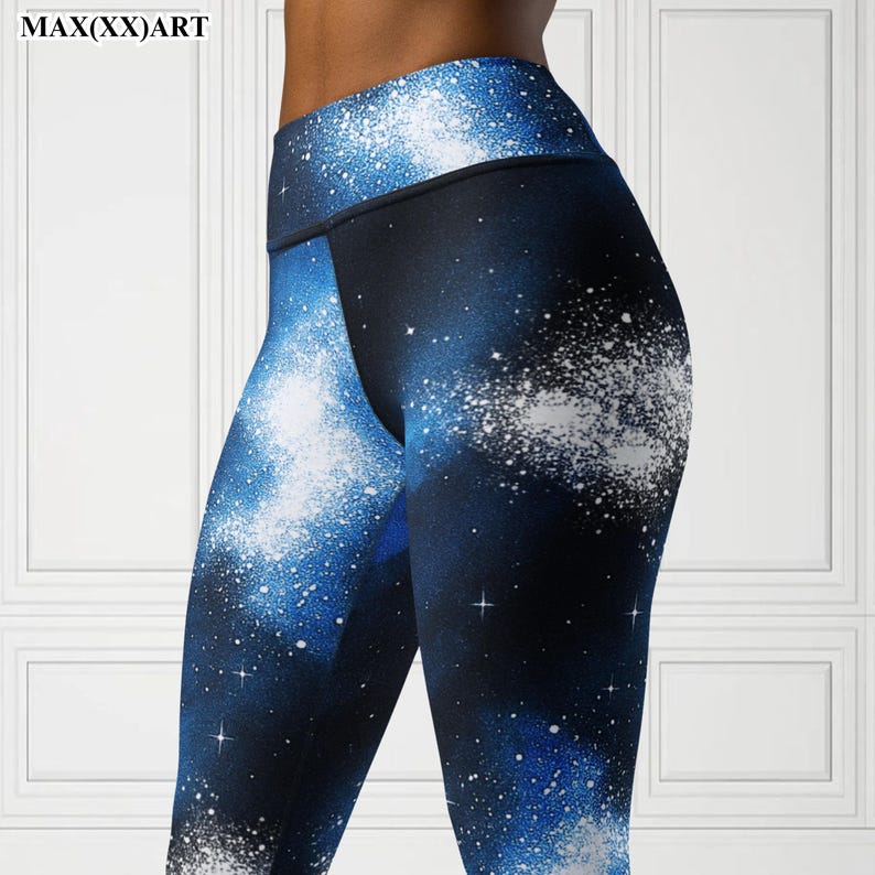 Puede incluir: Leggings de cintura alta con un estampado de galaxia vibrante. Los leggings presentan un fondo azul oscuro con salpicaduras blancas y azul claro y detalles en forma de estrella. El texto "MAX(XX)ART" es visible en la esquina superior izquierda.