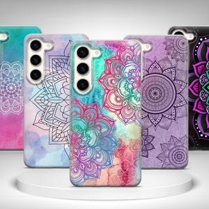 Può includere: Una collezione di cinque custodie per telefono con disegni mandala. Le custodie presentano una varietà di colori, tra cui rosa, blu, viola e nero. Ogni custodia ha un motivo mandala unico in bianco o nero.