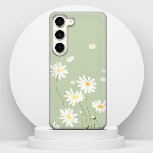 May include: A clear phone case with a pale green backdrop, decorated with a daisy floral pattern. The daisies have white petals and yellow centres. The case has camera and button cutouts.