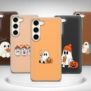 May include: Five smartphone cases in brown, beige, orange, and black colors, each featuring a different cartoon ghost illustration. The designs include ghosts with pumpkins, coffee cups, and a knife, with the text Boo! on the dark brown case.
