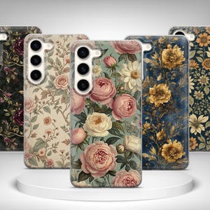 Peut inclure: Cinq coques de téléphone avec des motifs floraux. Les coques présentent divers motifs de fleurs, notamment des roses et des tournesols, dans des tons de rose, de jaune et de bleu. Les coques sont exposées sur une plateforme circulaire blanche.