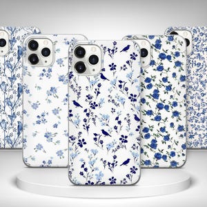 May include: Five phone cases with floral and bird designs. The cases feature white backgrounds with blue floral patterns, including roses, butterflies, and birds. The cases are displayed on a white platform.