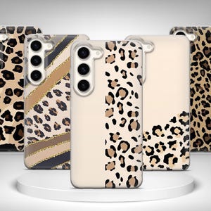 Puede incluir: Una colección de fundas para teléfonos con varios diseños. Las fundas presentan estampados de leopardo en tonos marrón y negro, junto con rayas doradas y beige. Algunas fundas tienen un fondo beige liso con detalles de estampado de leopardo.