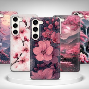 May include: Five phone cases with floral and landscape designs. The cases feature pink cherry blossoms, a crane, mountains, waterfalls, and a Japanese pagoda. The cases are displayed on a white circular stand.