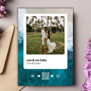 Könnte beinhalten: Eine Grußkarte mit einem Foto eines Paares am Strand, umrahmt von einem weißen Rand. Die Karte zeigt den Text "you & me baby" und die Namen "Lisa & Calos". Der Hintergrund hat ein blaues Ozean-Design mit Musikplayer-Symbolen.