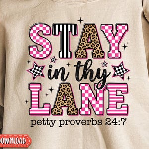 May include: A beige sweatshirt featuring the phrase "STAY in thy LANE" in pink, black, and leopard print. The text "petty proverbs 24:7" is below. The design incorporates stars and a checkered pattern.
