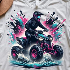 May include: White t-shirt featuring a colorful graphic of a person riding an ATV through water. The ATV is black and pink, with splashes of pink and teal. The words "INSTANT DOWNLOAD" and "DIGITAL DOWNLOADS" are visible.