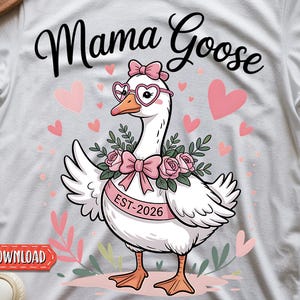 Könnte beinhalten: Weißes T-Shirt mit dem Text "Mama Goose" in Schreibschrift. Das Shirt zeigt eine Cartoon-Gans mit herzförmiger Brille und einer rosa Schleife. Die Gans hat ein rosa Band mit der Aufschrift "EST-2026". Rosa Herzen und florale Elemente umgeben die Gans.