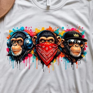 May include: White t-shirt featuring three cartoon monkeys with colorful paint splatter. One monkey wears headphones, another a red bandana, and the third a black cap and sunglasses. The shirt has the text "DIGITAL DOWNLOADS".