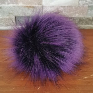 Peut inclure: Un pompon en fausse fourrure violet et noir. Le pompon est moelleux et doux.