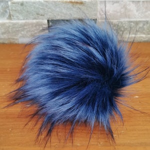 May include: A fluffy blue faux fur pom pom. The pom pom is made of soft, synthetic fur and is perfect for adding a touch of whimsy to any hat or accessory.