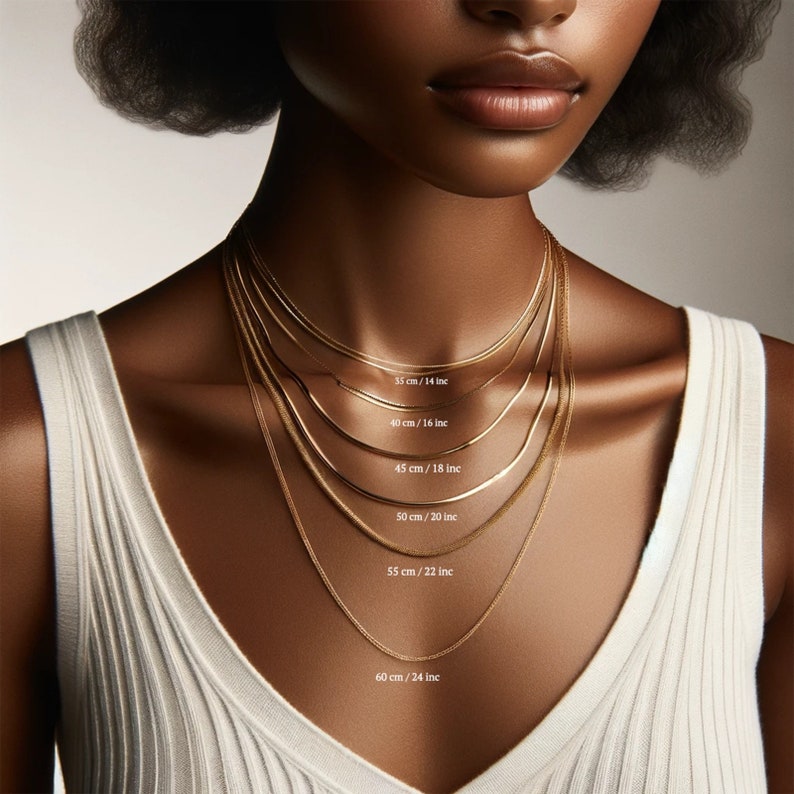 May include: A close-up of a model wearing six different gold chain necklaces, each with a different length. The lengths are labeled in inches and centimeters.