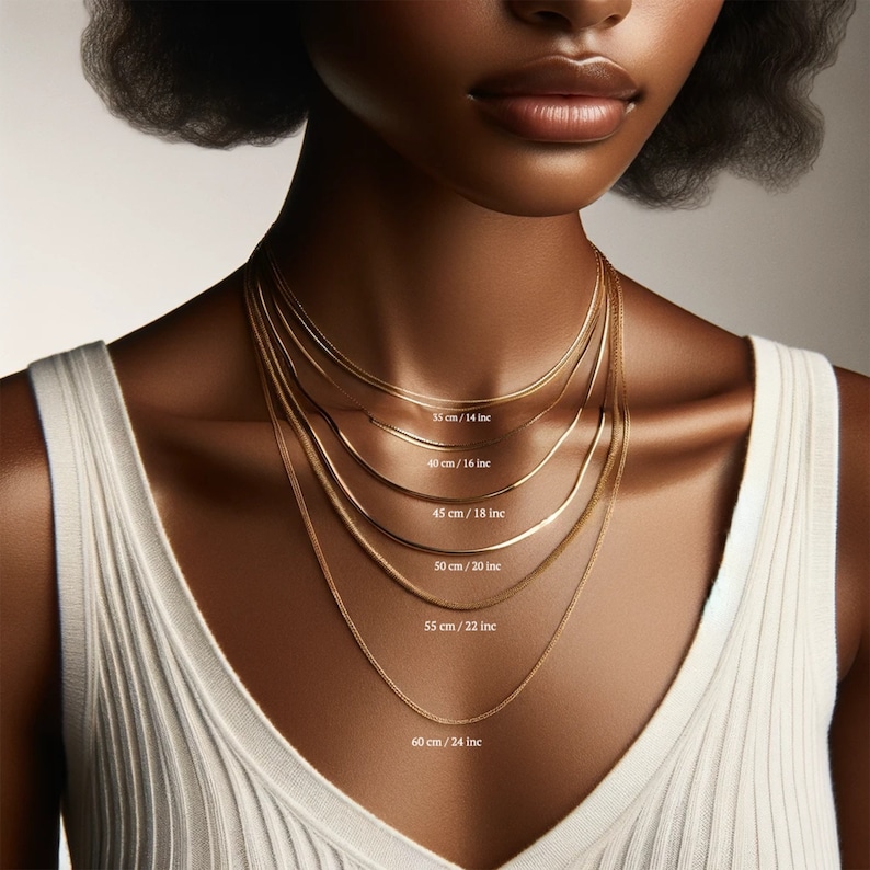May include: A close-up of a model wearing six different gold chain necklaces, each with a different length. The lengths are labeled in inches and centimeters.
