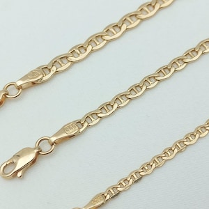 May include: Three gold chains with a mariner link pattern. The chains are of different lengths and are laid out on a white surface.