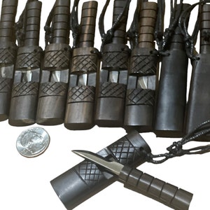 Puede incluir: Un grupo de 10 colgantes de cuchillo de madera con un cordón negro. Los cuchillos están hechos de madera oscura y tienen una hoja plateada. Los colgantes están todos en fila y el cordón está atado alrededor de la parte superior de cada colgante. Hay una moneda de 25 centavos de dólar estadounidense en la imagen para la escala.
