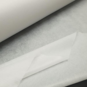 Pode incluir: Um rolo de tecido de entretela branco, um tipo de material fusível usado em costura e artesanato.