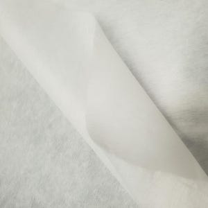 Może przedstawiać: Biała tkanina usztywniająca, rodzaj materiału termoplastycznego stosowanego w projektach szycia i rękodzieła.