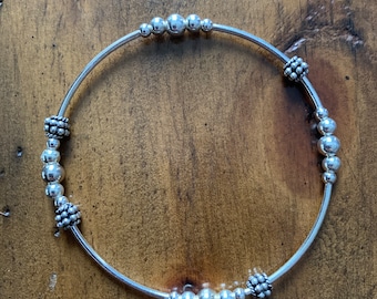 Sterling silver stretch layering bracelet with round beads and silver floating Bali beads.