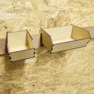 May include: Two small wooden boxes with brown stain, mounted on a wall. The boxes are open and empty.