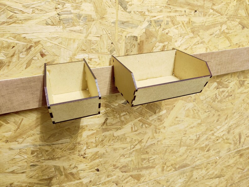 May include: Two small wooden boxes with brown stain, mounted on a wall. The boxes are open and empty.