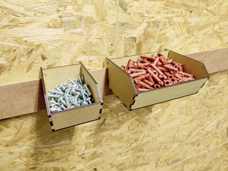 May include: Two wooden storage bins with a brown finish. The bin on the left is filled with silver screws. The bin on the right is filled with red plastic anchors.