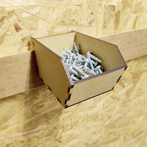 May include: A small wooden box with a lip on the front, mounted to a wall, filled with silver screws.