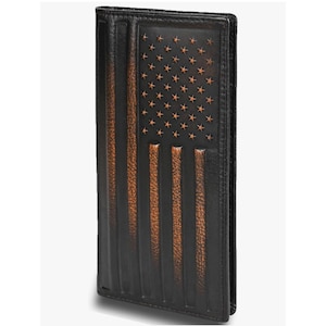 May include: A tall, rectangular black leather wallet featuring an embossed American flag design. The flag pattern includes raised stars in the upper corner and vertical stripes, with a distressed brown finish highlighting the textured leather surface.