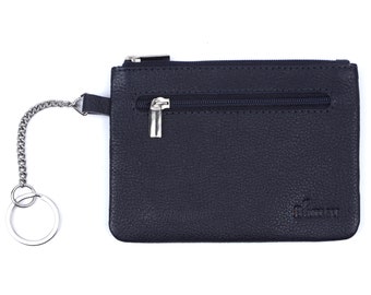May include: A black leather coin purse with a silver zipper and a silver chain with a key ring. The purse has the word "Baman" embossed on the front.