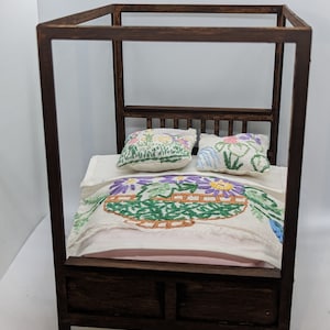 May include: A wooden four-poster bed with a pink and white embroidered bedspread and two floral patterned pillows.