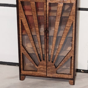 May include: A wooden cabinet with glass doors and a sunburst design. The cabinet has a dark brown stain and is made of wood.