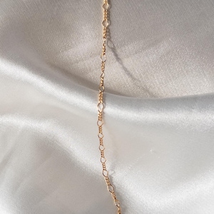 May include: A gold chain bracelet with a delicate, linked design.