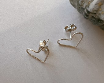 May include: A pair of silver heart-shaped earrings with a textured wire design. The earrings are simple and elegant.
