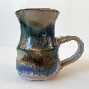 Peut inclure: Ensemble de trois tasses en céramique avec une finition mate et mouchetée. Les tasses sont de couleur crème, gris clair et gris foncé. Chaque tasse a un design simple et minimaliste avec une anse arrondie.