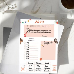 Könnte beinhalten: Ein druckbarer Vorsatzvertrag für 2023 mit rosa Hintergrund. Der Vertrag enthält einen Abschnitt für Ziele, eine Nachricht an dein zukünftiges Ich und einen Kalender, um den Fortschritt während des Jahres zu verfolgen.