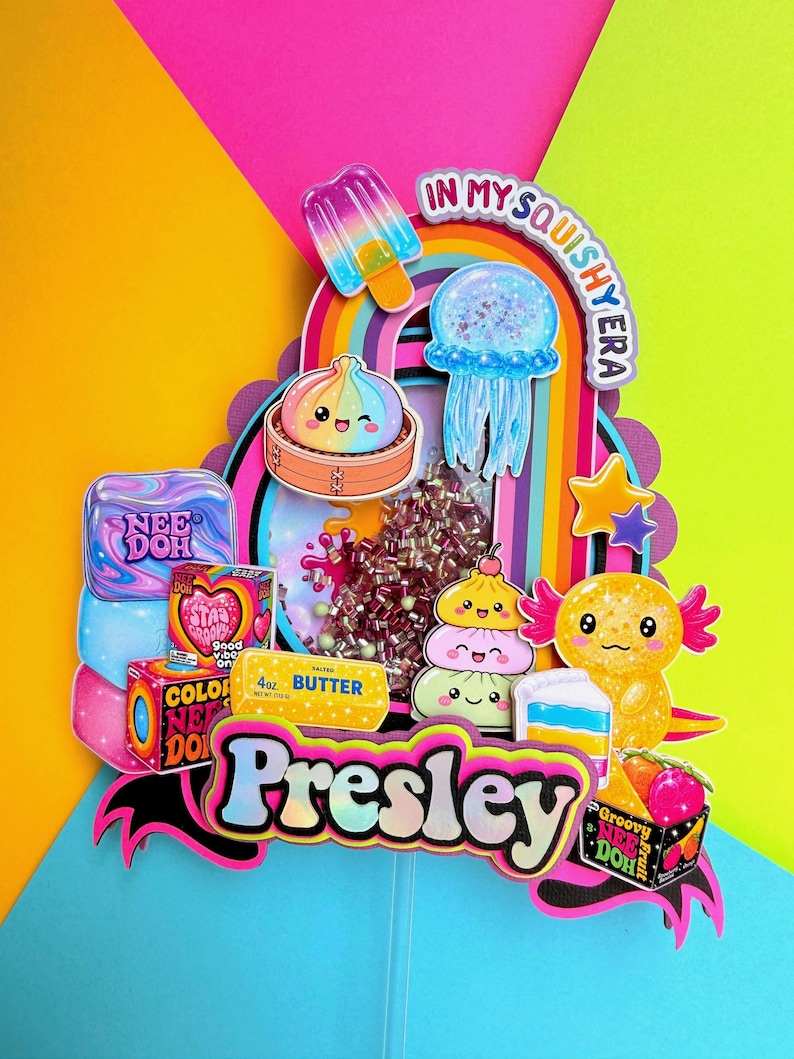 Puede incluir: Un adorno para pastel de varias capas con el nombre Presley en letras negritas, rodeado de recortes coloridos de un arco&iacute;ris, paleta, medusa, ajolote y varios paquetes de juguetes Nee Doh, con el texto In My Squishy Era en la parte superior.