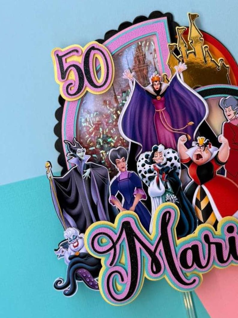May include: A colorful cake topper featuring Disney villains, the number 50, and the name "Mari". The topper has a black scalloped edge, pink and blue accents, and a castle silhouette. The Evil Queen, Ursula, and Cruella de Vil are among the characters.