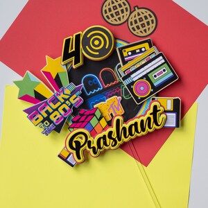 May include: A colorful cake topper with a 40, a Rubik's Cube, a cassette tape, a boombox, a disco ball, and the text "Back to the 80's" and "Prashant".