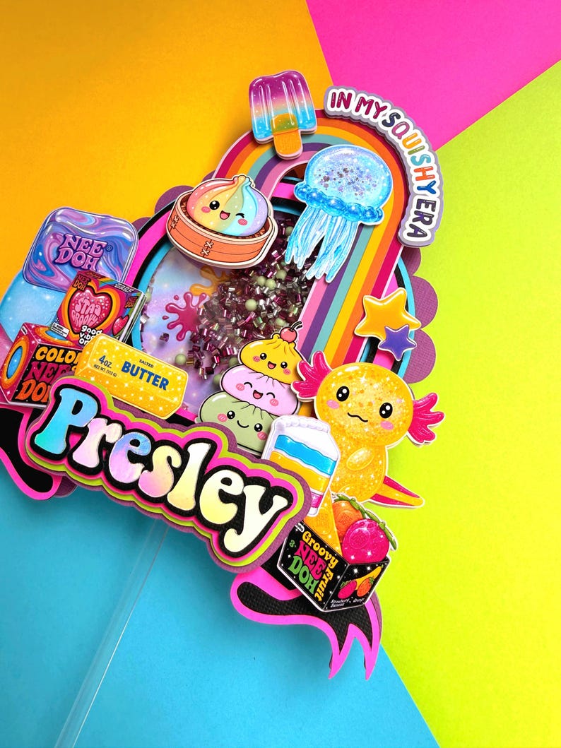 Puede incluir: Un adorno para pastel de varias capas con el nombre Presley en letras azules y amarillas. El dise&ntilde;o incluye gr&aacute;ficos coloridos de un helado, medusa, ajolote, dumplings y empaques de Nee Doh con el texto In My Squishy Era.