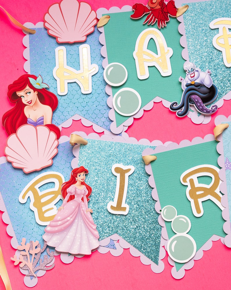 May include: A colorful banner with the words "Happy Birthday" in gold letters. The banner features a mermaid, a seashell, and bubbles. The banner is perfect for a mermaid-themed birthday party.