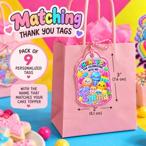 Puede incluir: Una bolsa de regalo de papel rosa con una etiqueta de agradecimiento personalizada sujeta por un cordel rojo y blanco. La etiqueta muestra dulces de dibujos animados coloridos y el texto "THANK YOU FOR CELEBRATING WITH ME! Emma". Mide 7,6 cm por 5,1 cm.