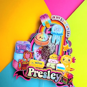 Puede incluir: Un adorno para tarta multicapa que presenta el nombre Presley en letras negritas. El dise&ntilde;o incluye ilustraciones coloridas de un polo, una medusa, una empanadilla, un ajolote y varios paquetes de Nee Doh, con el texto In My Squishy Era.