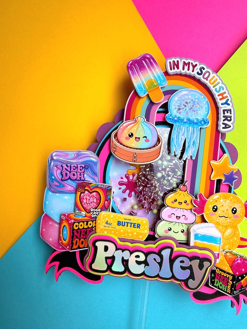 Puede incluir: Un adorno para pastel de varias capas con el nombre Presley en letras grandes, rodeado de recortes coloridos de un arco&iacute;ris, una paleta, una medusa, un dumpling, un ajolote y art&iacute;culos de Nee Doh con el texto In My Squishy Era.
