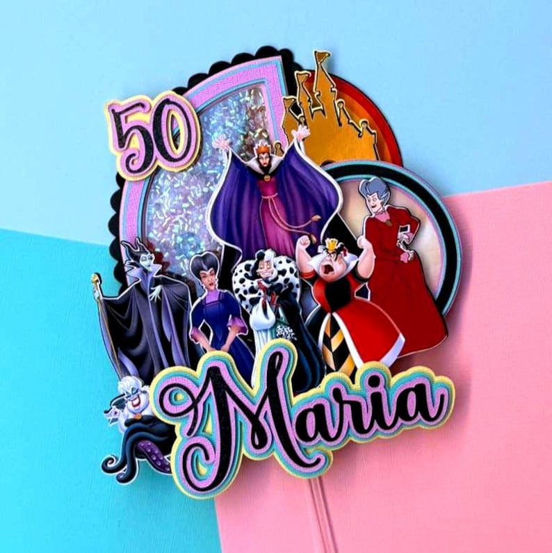May include: A colorful cake topper featuring Disney villains, the number 50, and the name "Maria". The design includes characters like Maleficent and the Evil Queen, set against a pink and blue background. A castle silhouette is also included.